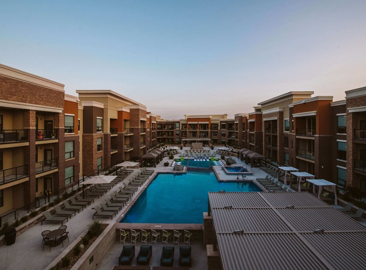 view of u shaped apartment complex with an outdoor pool in the center and rows of seating on the patio